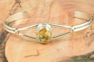 Genuine Boulder Turquoise set in Sterling Silver Bracelet. The cabochon is Boulder Turquoise, you can see the veins of Turquoise running through the host rock. The Boulder Turquoise Mine is located in northeast Nevada. It was discovered in 1970 by a Shoshone sheep herder. Production is small due to the remote location and winter weather. Boulder Turquoise is valued for both it's beauty and rarity. Every stone is unique. Created by Navajo Artist Larson Lee.. 